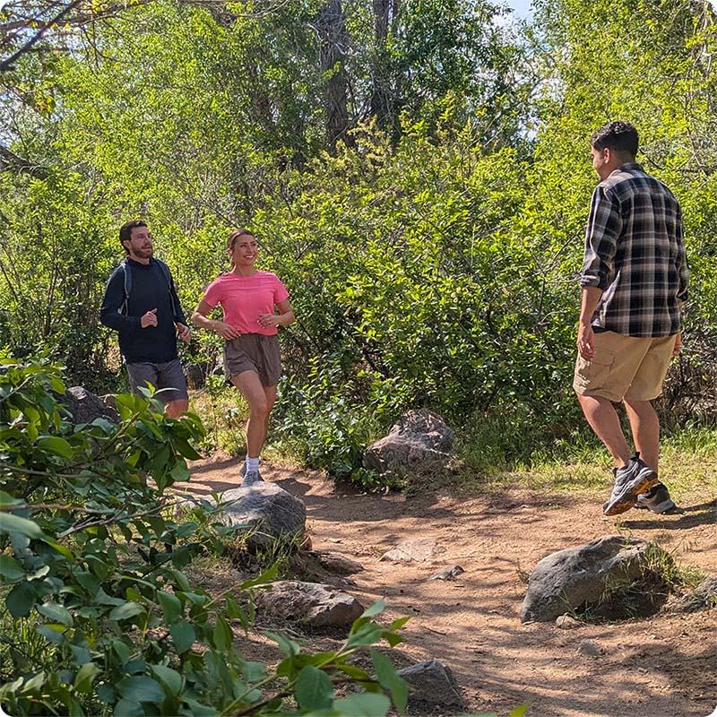 Two runners smiling at a hiker